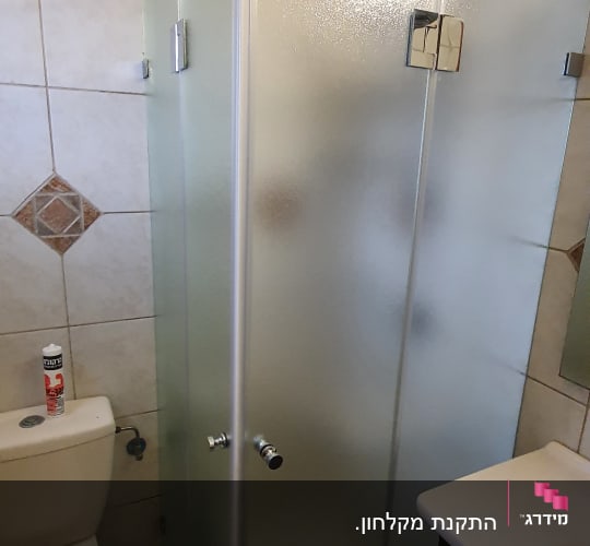 מקלחון פינתי מזכוכית חלבית מותקן בחדר רחצה